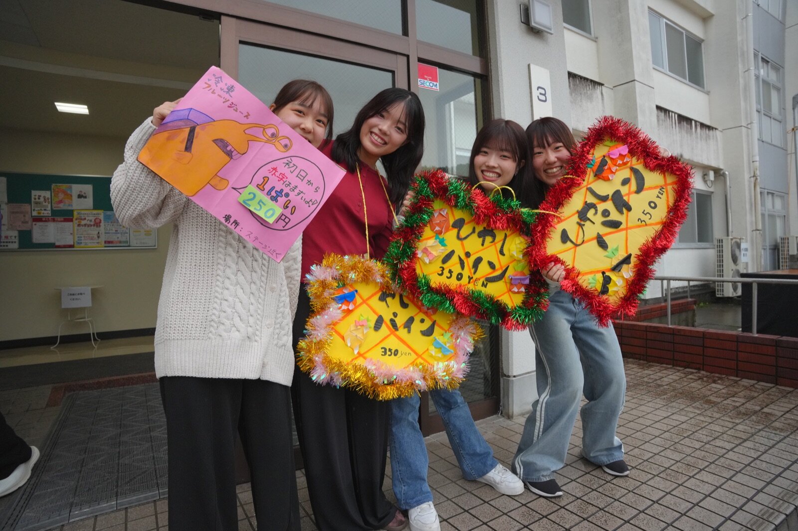 冷凍フルーツジュースとひやしパインの看板を持つ学生